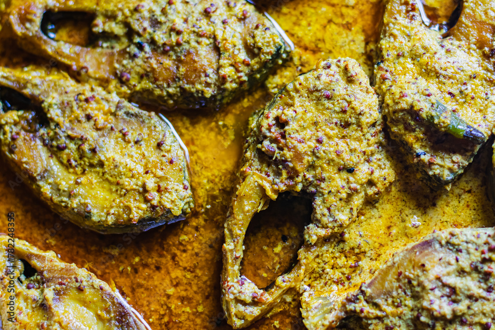 Sorshe ilish or hilsa fish curry cooked with mustard seeds. It is a very famous Bengali dish. Pieces of fish are seen in rich yellow gravy. This is traditional delicacy in Bengali culture. Sorshe ilish or hilsa fish curry cooked with mustard seeds. It is a very famous Bengali dish. Pieces of fish are seen in rich yellow gravy. This is traditional delicacy in Bengali culture.
