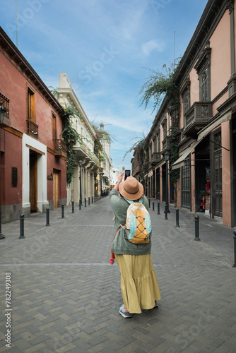 Tourist woman taking a photo in a traditional Lima street.