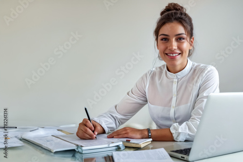 Ritratto di una Businesswoman Felice al Lavoro in un Ufficio Luminoso con un Blocco Note e Notebook II photo