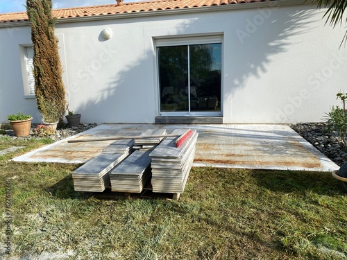 Construction de terrasse en carrelage sur chape de ciment devant maison 