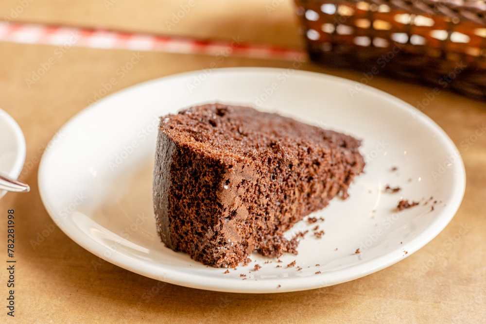 Piece of fresh homemade chocolate sponge cake on white plate on the table