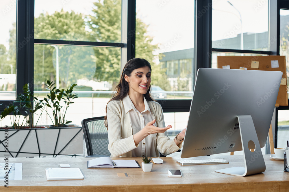 A businesswoman is deeply focused while sitting at a desk with a computer in a modern office environment. A businesswoman is deeply focused while sitting at a desk with a computer in a modern office environment.