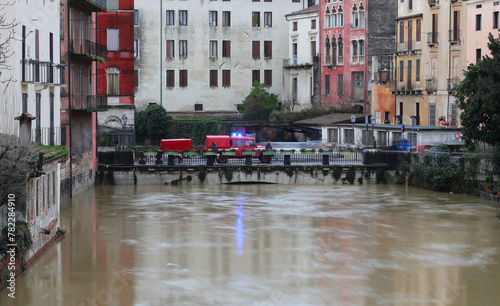 Firefighting vehicles and swollen river during flood, water lapping at houses about to overflow © ChiccoDodiFC