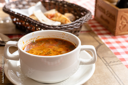 Minestrone  Italian vegetable soup in white bowl on served table in a caf   or restaurant  copy space