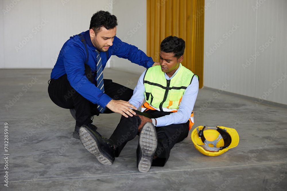worker fall down on the floor with hurting knee and businessman helping him in the factory worker fall down on the floor with hurting knee and businessman helping him in the factory