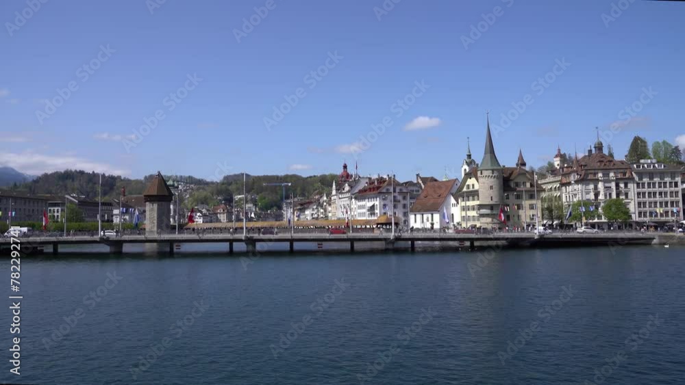 Arriving at pier of Swiss City of Lucerne with famous covered wooden Kappel Bridge and water tower in the background on a sunny spring day. Movie shot April 11th, 2024, Lucerne. Arriving at pier of Swiss City of Lucerne with famous covered wooden Kappel Bridge and water tower in the background on a sunny spring day. Movie shot April 11th, 2024, Lucerne.