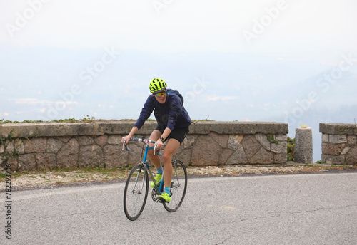 Fototapeta Naklejka Na Ścianę i Meble -  young cyclist powers up steep mountain road during grueling cycling race