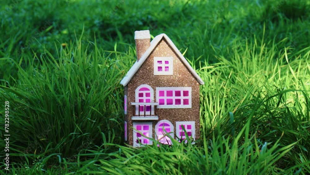 Beautiful brown house among green grass with pink and purple lights in the windows Beautiful brown house among green grass with pink and purple lights in the windows
