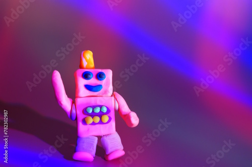 A funny plasticine robot dances on a colored background.
