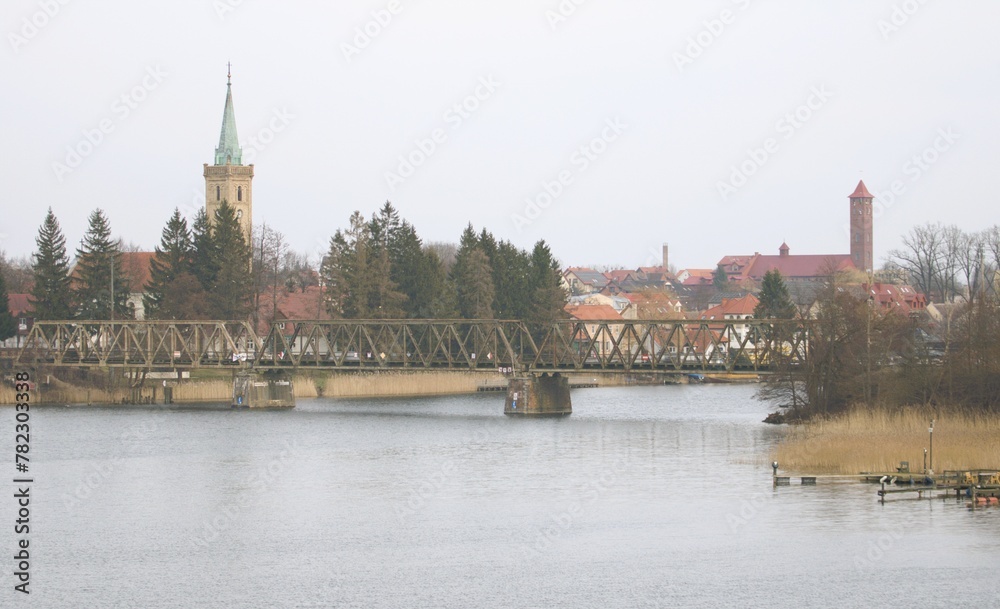 an old railway bridge over the river in the foreground and city buildings with church towers in the background