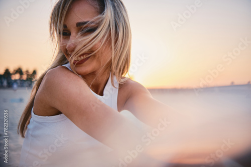 The image captures the contemplative silhouette of a woman in white facing a beautiful sunset, suggesting introspection and calm