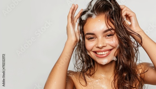 Gorgeous woman with charming smile washing hair against white backdrop