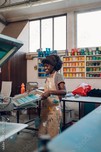 Interracial printing shop worker preparing silkscreen machine for printing