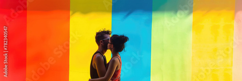 guy and girl, happy couple in love, kissing couple on the background of a bright rainbow wall, hugs and tenderness, romantic moment, striped