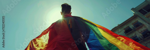 LGBT Pride Month, International Day Against Homophobia, guy with his back, lgbt flag against the sky, lgbt parade