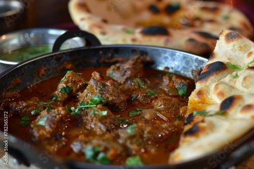 Spicy Indian lamb curry in steel karahi with naan photo
