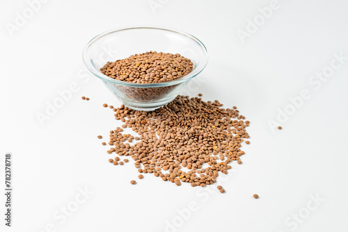 the lentils are in a glass bowl and scattered side by side on a white background