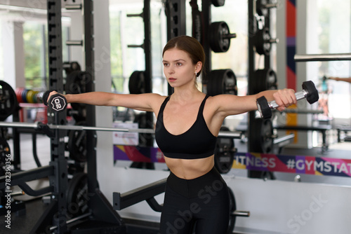 fit woman does fitness exercises with dumbbells in fitness gym