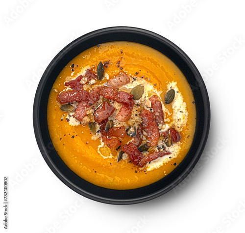 Pumpkin cream soup with crispy bacon isolated on white background, top view