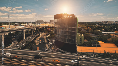 Closeup sun cityscape: traffic highway with cars at skyscrapers aerial. Modern buildings at roadside. Manila town streets of business center at sunlight. Philippines metropolis city at close-up shot