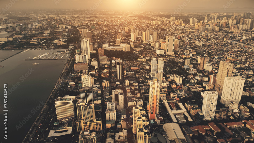 Fototapeta premium Metropolis city at sea bay sunrise aerial. Philippines capital cityscape at sun rise light. Urban streets with modern buildings at roads, highways. High skyscrapers at sunlight. Cinematic summer town