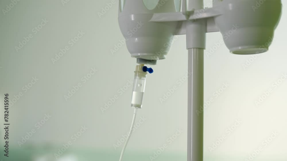 Closeup view of IV drip in hospital. Close-up of intravenous saline solution in medical clinic in light bright interior. Saline solution drip for patient in hospital, no people, nobody, slow motion.