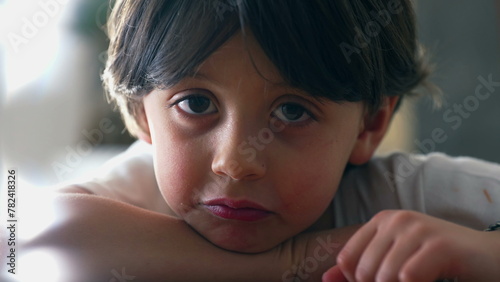 Fotografie One small boy shrugging shoulders displaying doubt while in deep mental reflecti