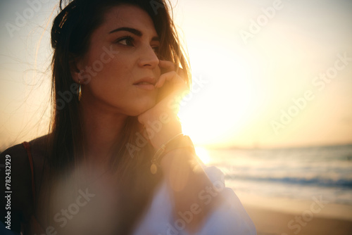 Artistic close-up of a woman's face with sun flare effect and contemplative expression