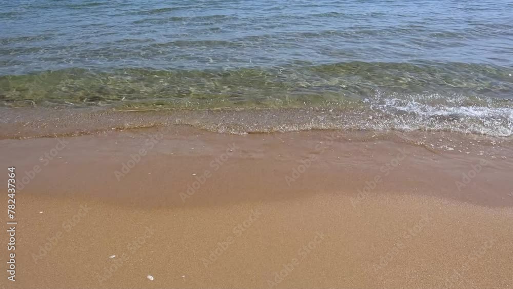 Close-up of waves lapping on the shore of a sandy beach.