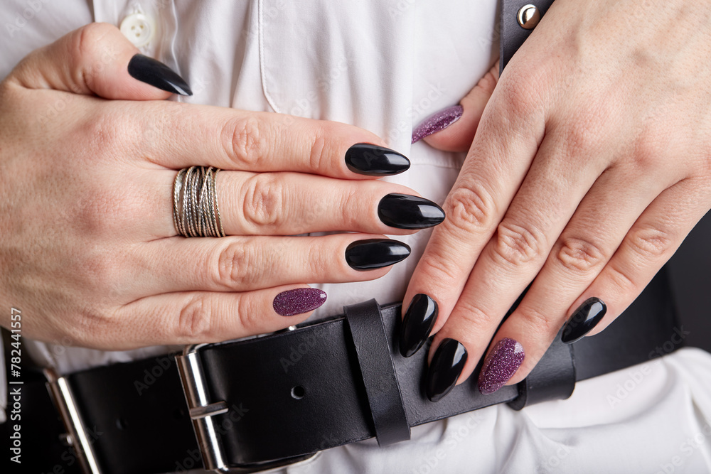 Hands with natural manicured nails color with black and purple nail polish. Fashion and stylish manicure.