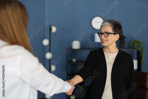 In a professional setting, a businesswoman and her colleague share a handshake, symbolizing successful teamwork. © Andrii Zastrozhnov