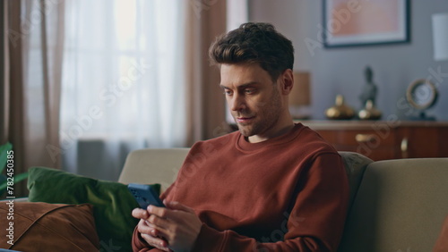 Foto Angry man swiping cellphone screen reading message with bad news at home closeup