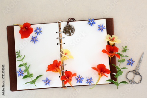 Herb and flower preparation for cold and flu remedy with borage, nasturtium and lemon balm with old leather recipe book. Natural alternative herbal medicine on hemp paper background.