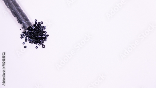 transparent tube pouring black beads on white background