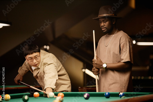 Sepia portrait of two young men playing pool together in low lighting copy space