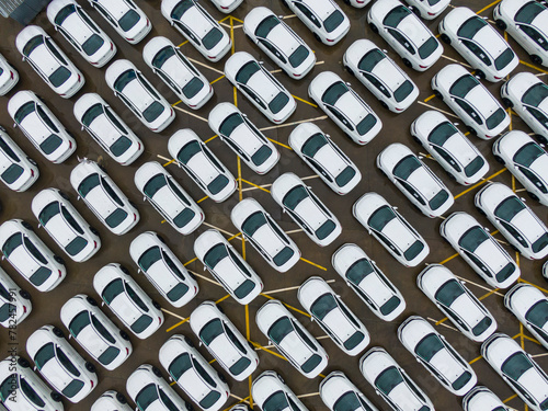 A large parking lot full of white cars. Cars leaving the car factory are waiting at the port for sale and transportation.