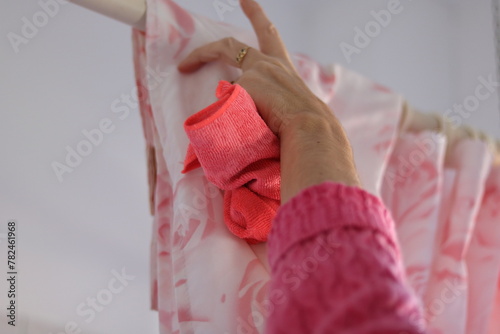 Woman cleaning bathtub curtain using rag cloth and soap spray 