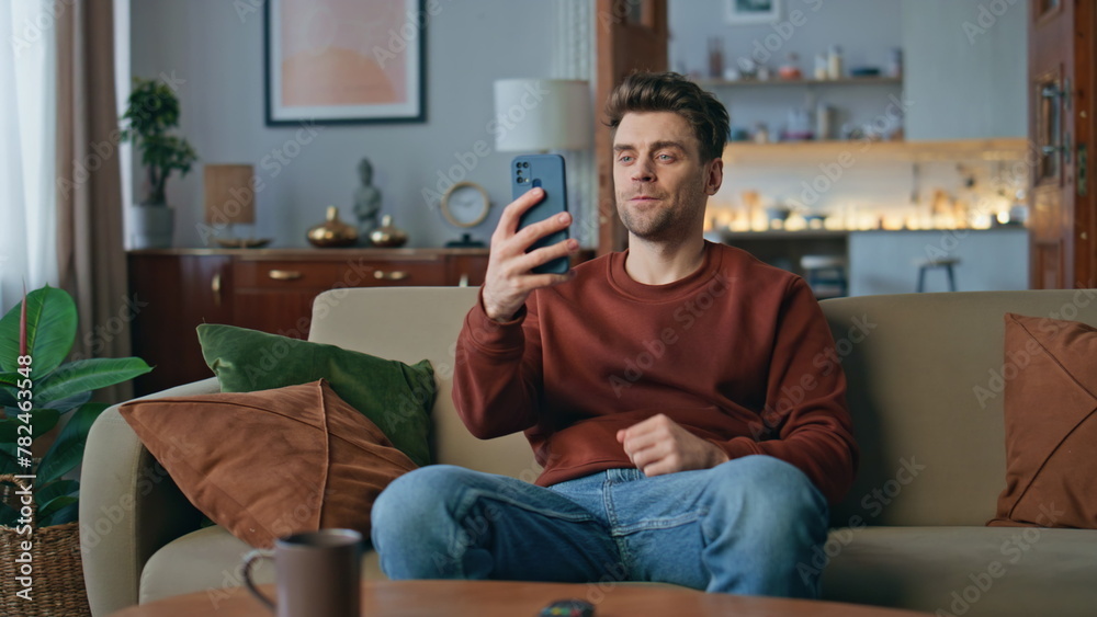 Joyful hipster waving web camera smartphone at home. Smiling guy video call Joyful hipster waving web camera smartphone at home. Smiling guy video call