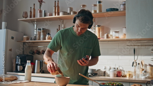 Man listening music cooking in wireless headphones at modern kitchen closeup