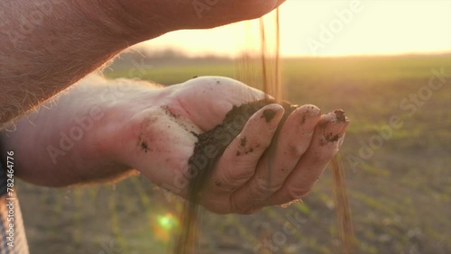 Farmer's hands hold handful of fertile soil and pour it into other hand. Agriculture, agribusiness concept. Gardener holds fertilized earth in his palms. Agriculture fertility. Farmer working in field photo
