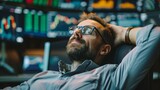 Contemplative man in glasses resting in office chair with blur stock market monitors.