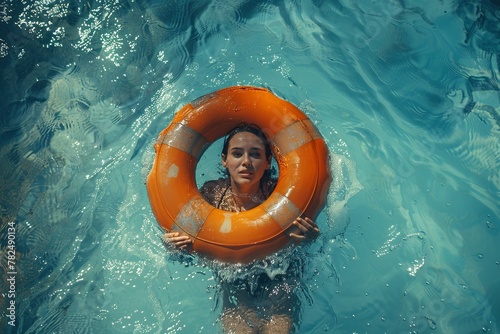A woman smiles happily while swimming in a pool with an orange life preserver