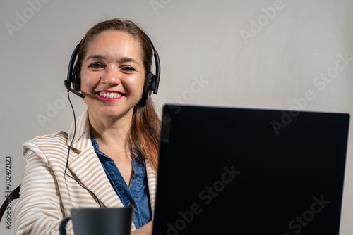 Mujer en una tele llamada, sonriente y mirando a cámara. Concepto de mesa de ayuda y asistencia virtual	 photo
