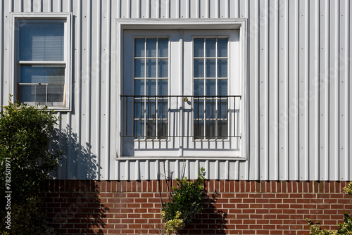 White Window on Corrugated Metal Siding Over Brick Foundation, Closed Metal Balcony