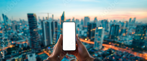 Hand holding smartphone with blank screen, cityscape during sunrise in the background. Mockup of a cell phone with transparent. Advertising and marketing. Banner. Copy space