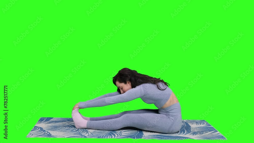 Young woman practicing yoga while sitting on yoga mat on the chroma key