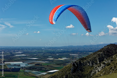 People enjoy the extreme sport of paragliding. Outdoor living in the blue sky. Incredible nature and views. Adventures and adrenaline with parachute. Travel destination Norma Latina Italy. Summer 