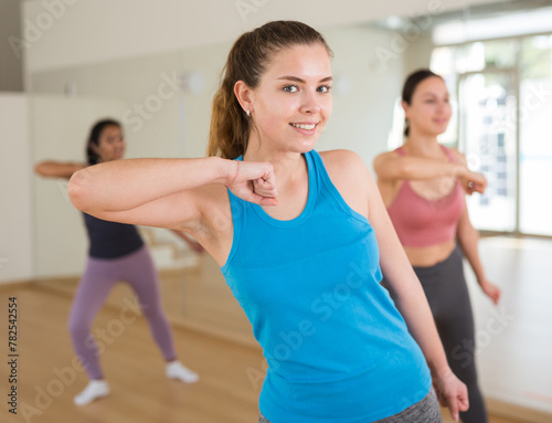 Young adult athletic woman dancing during group class in dance center