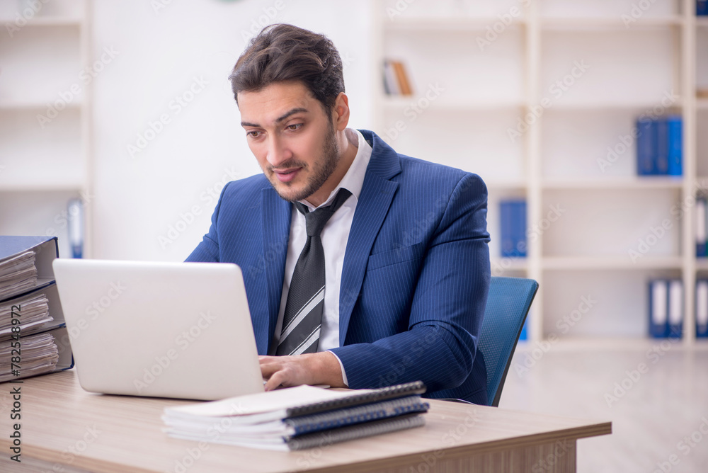Young male employee and too much work in the office Young male employee and too much work in the office