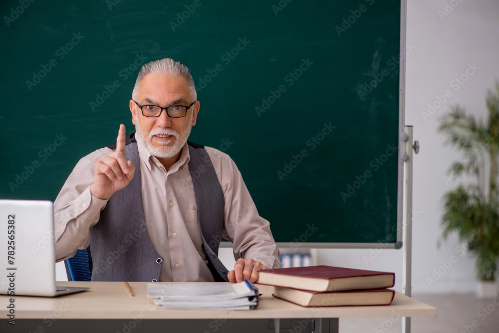 Old male teacher in the classroom Old male teacher in the classroom